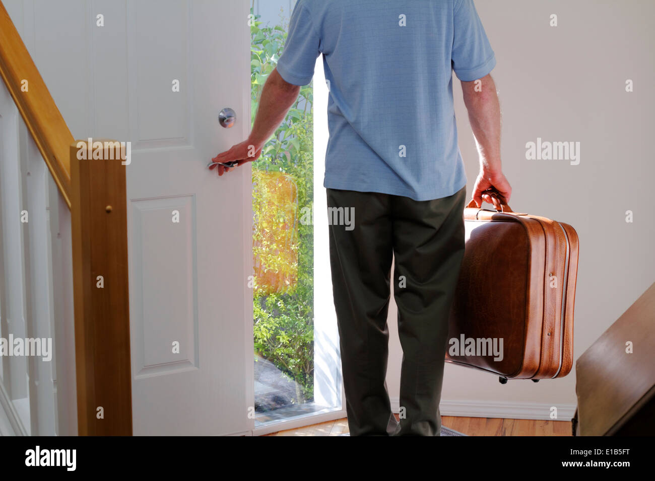 Un varón de mediana edad llevar una maleta a punto de dejar la casa. Un  hombre llevando una maleta a punto de salir a la puerta de su casa para  viajar Fotografía