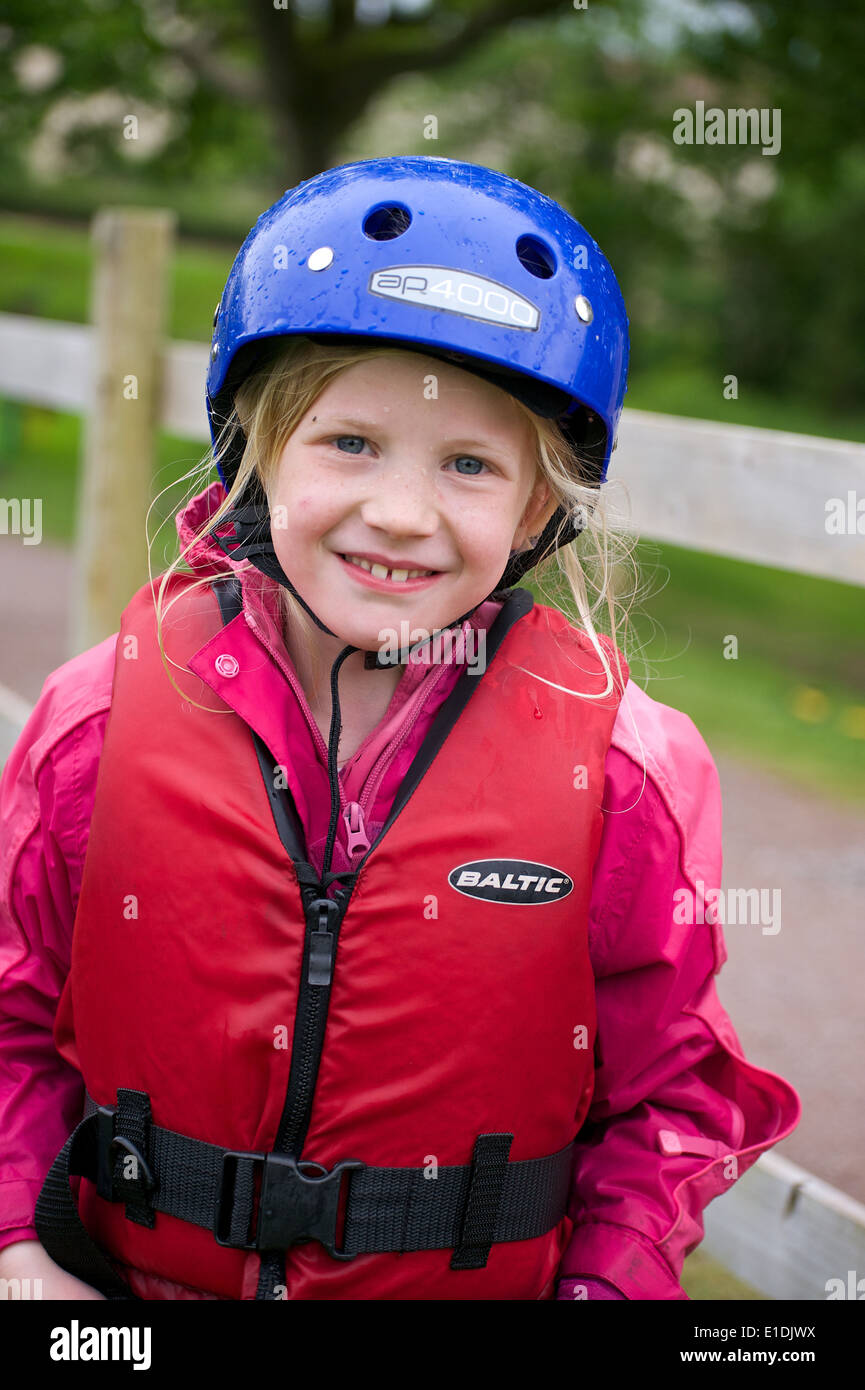 Joven rubia niña kid con casco y chaleco salvavidas participar en deportes acuáticos Foto de stock