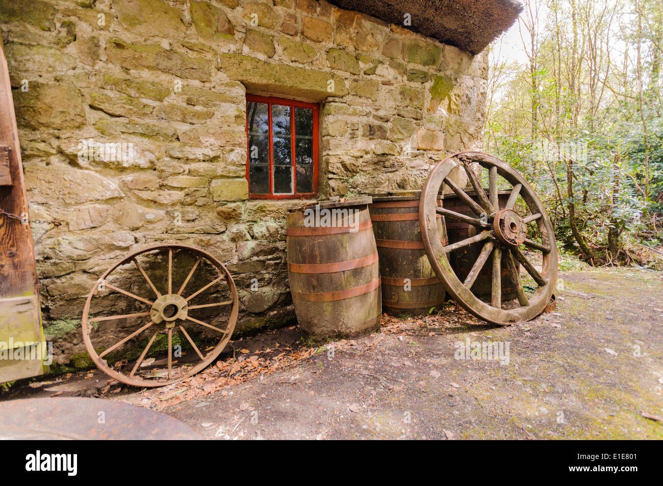 Barriles y vagón ruedas fuera una antigua casa de granja irlandesa Foto de stock