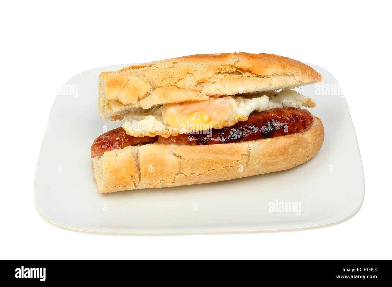 Huevo frito y salchicha baguette en una placa aislada contra un blanco Foto de stock