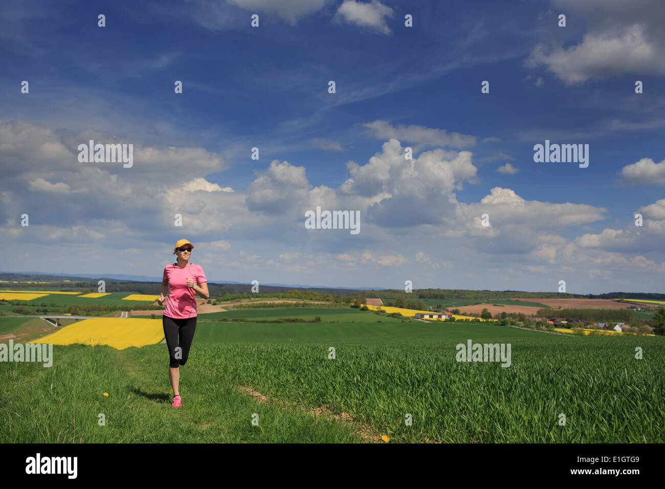 Mujer correr por los campos en la primavera Foto de stock