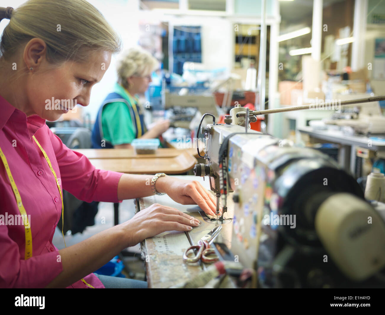 Coser trabajador en fábrica de ropa Foto de stock