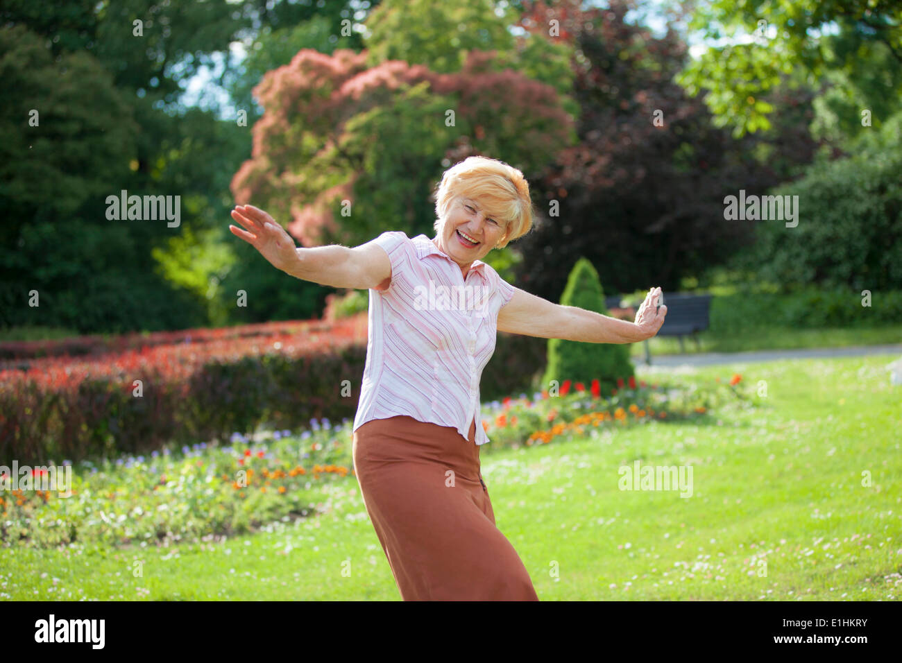 La alegría. Encantado juguetona mujer madura con los brazos estirados riéndose afuera Foto de stock