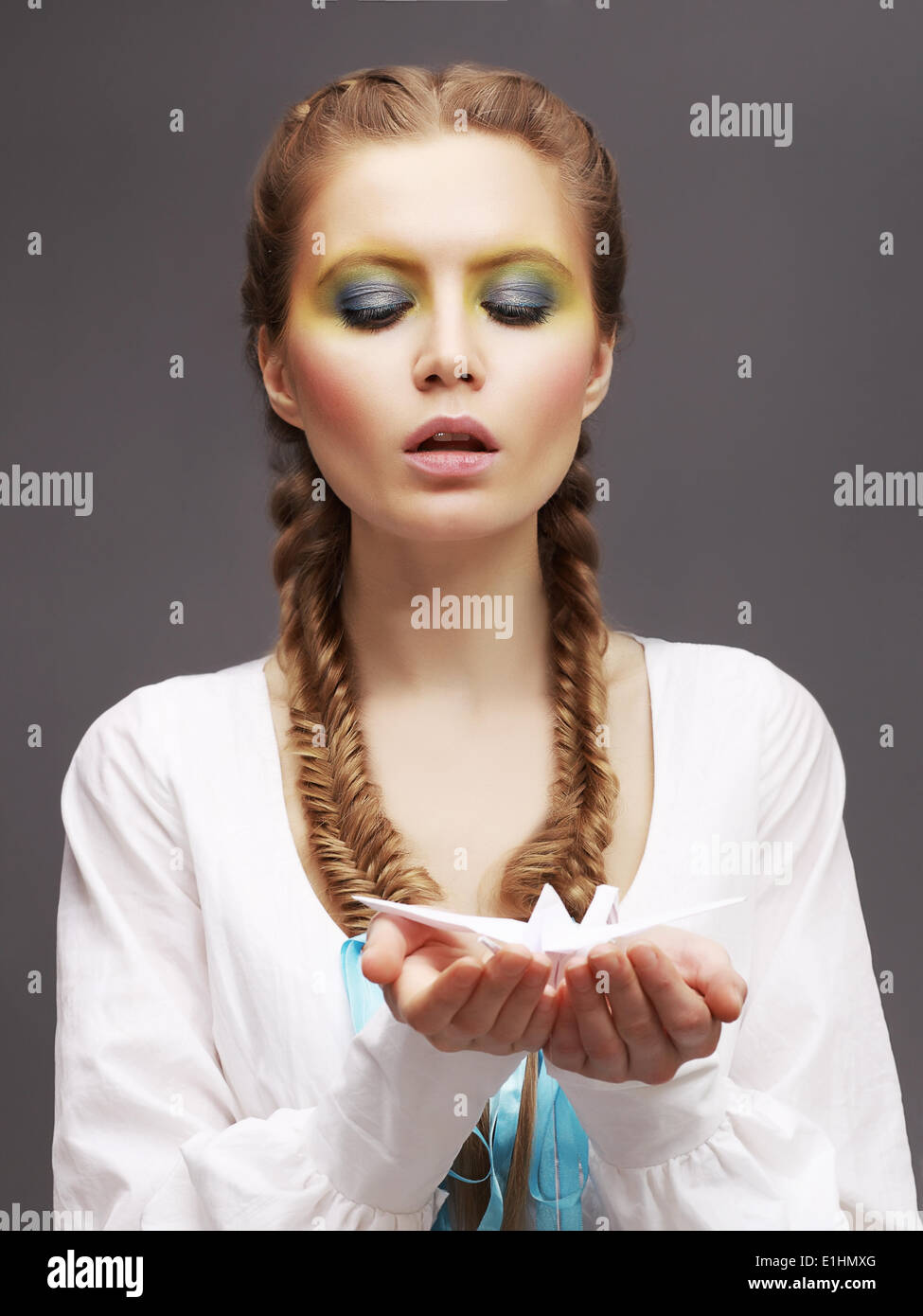 Aspiración. Mujer caucásica en vestido blanco liberando Origami Paloma. Amabilidad Foto de stock
