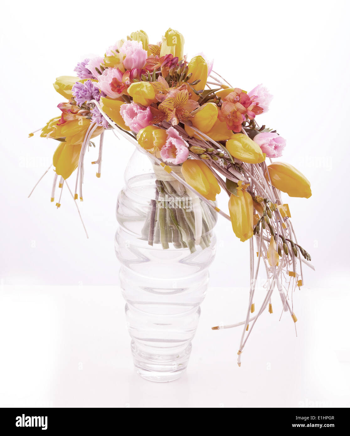 Patrón de flores coloridas arreglo en jarrón de cristal con tulipanes amarillo aislado en blanco Foto de stock