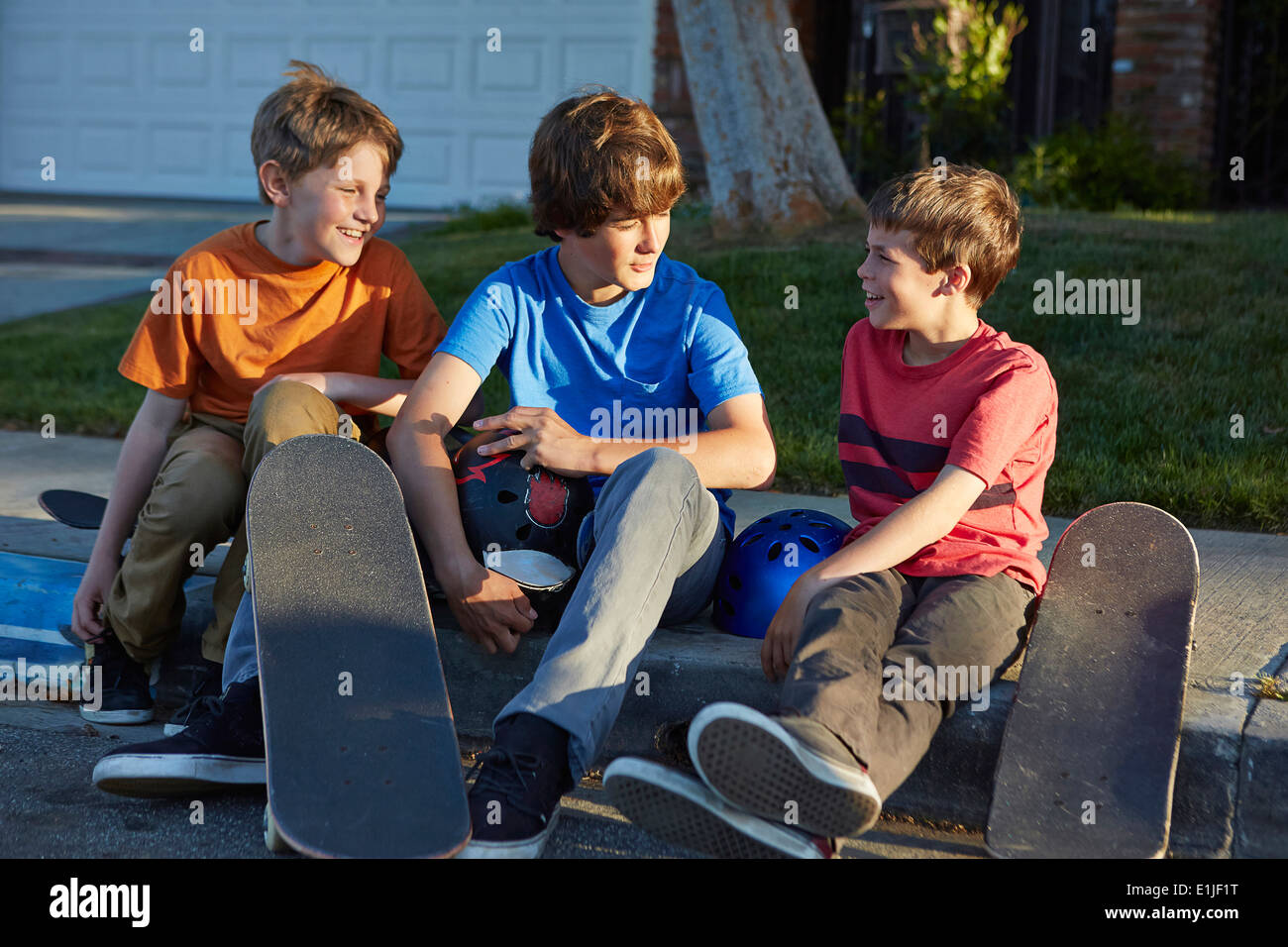 Los muchachos sentados sobre pavimento con skateboards Foto de stock