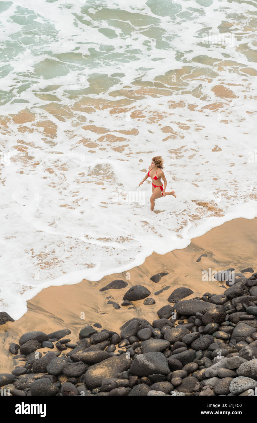 Foto de mujer corriendo veloz por la orilla de la playa do Stock