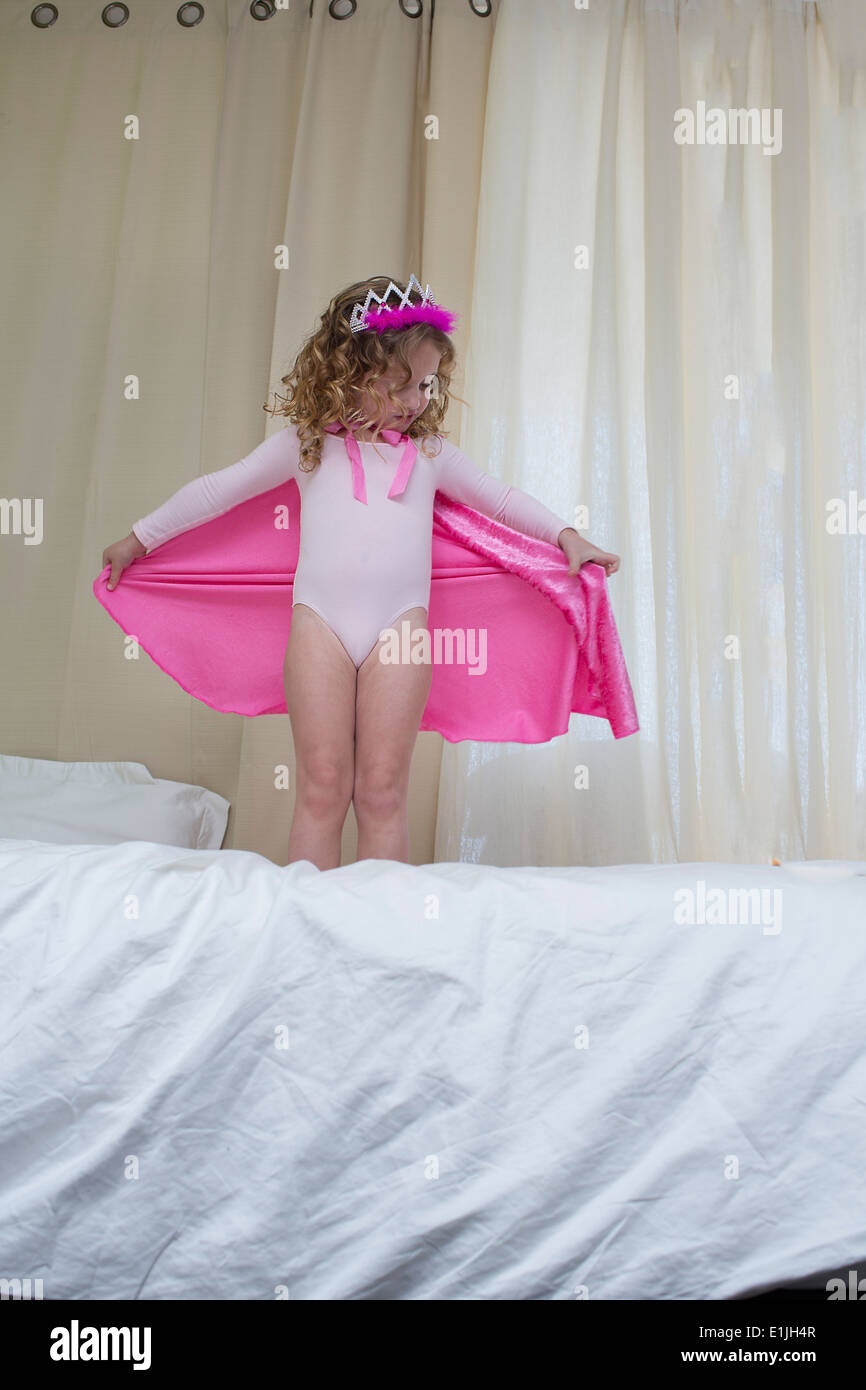 Niña vestida como una princesa de pie en la cama Foto de stock