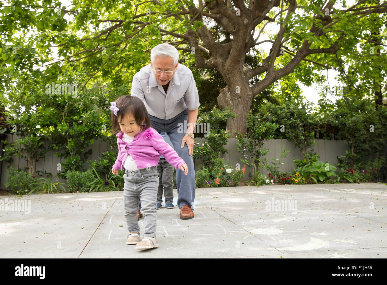 Abuelo jugando rayuela con un niño pequeño nieta Foto de stock