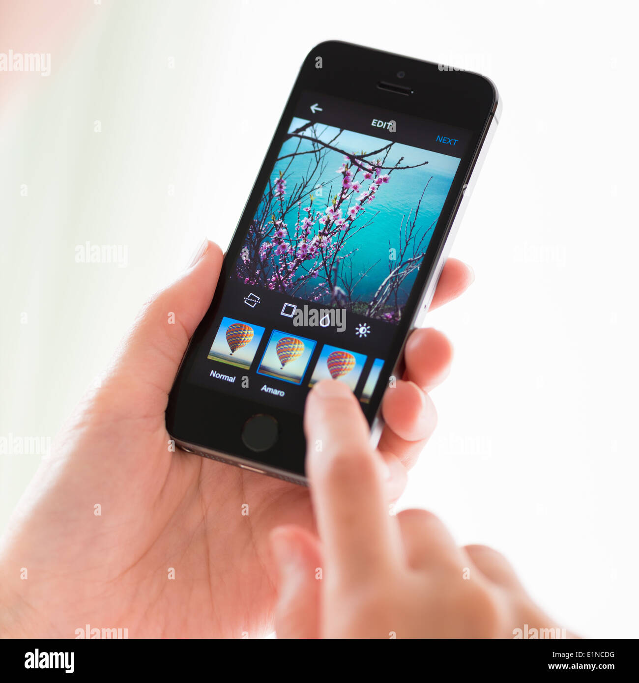 Persona aplicar filtros a la imagen digital en aplicación Instagram sobre un nuevo Apple iPhone 5S Foto de stock
