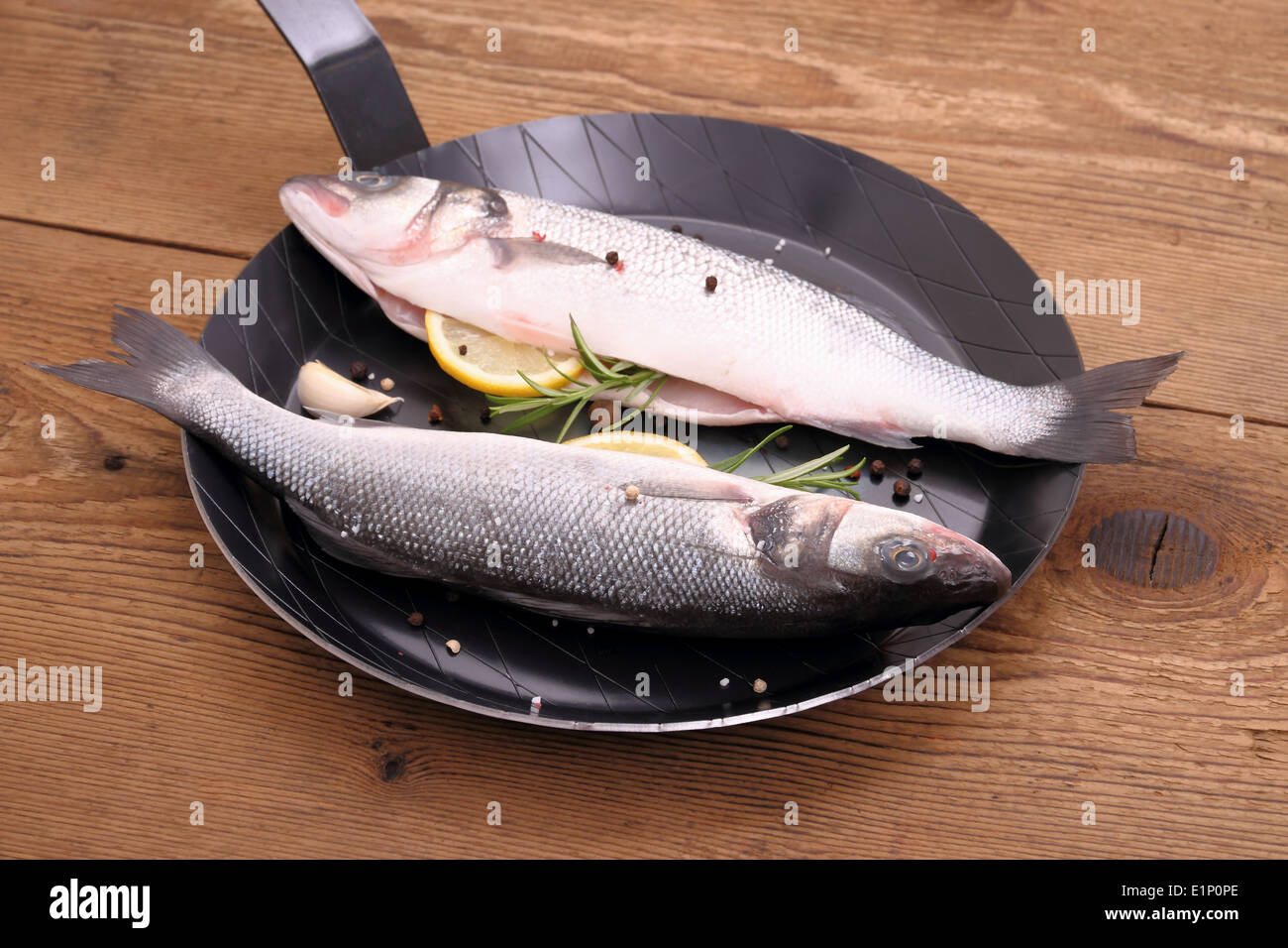 Dos lubina pescado fresco en la sartén con los ingredientes, horizontal Foto de stock