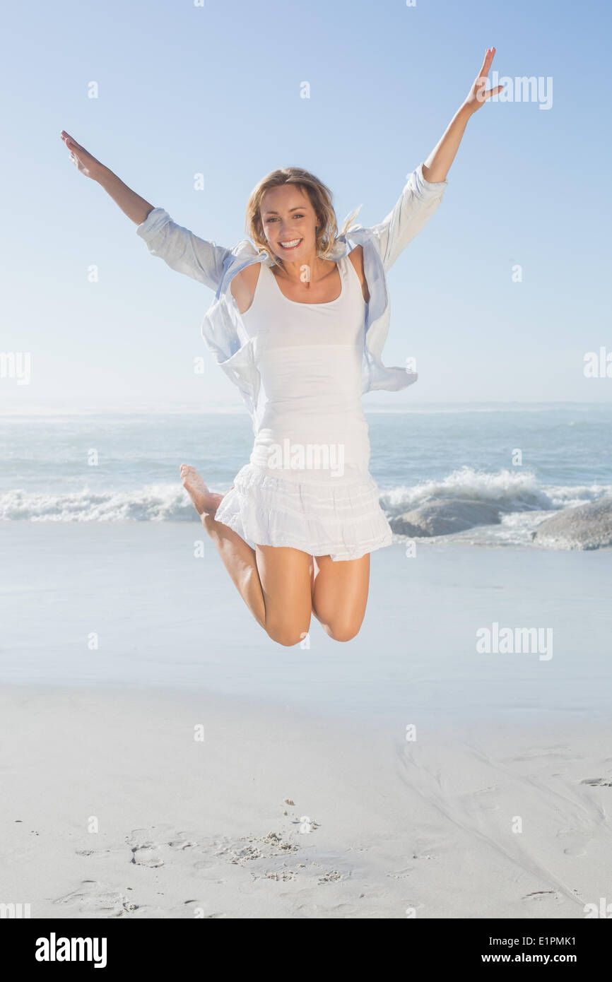 Rubia sonriente saltando por el mar Foto de stock