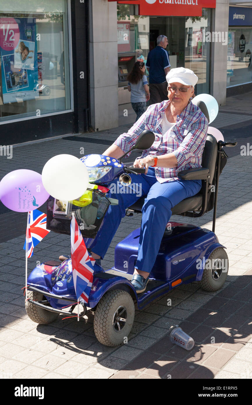 Persona en decorados movilidad scooter tomando parte en una caridad "maratón". Foto de stock