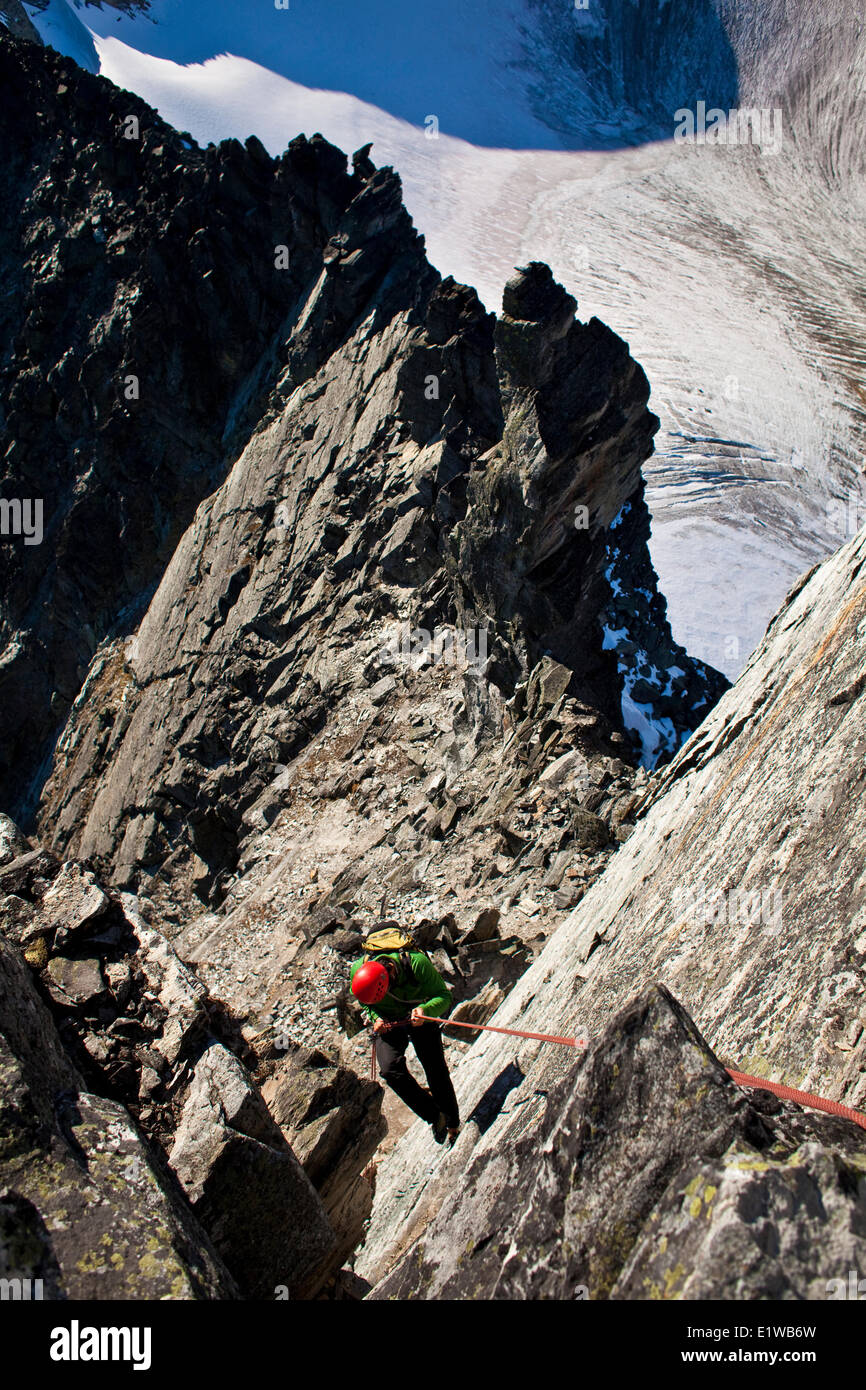 Un hombre escalador rappeles la arista oeste 5.6 después de alcanzar la cumbre del monte Tupper, Roger's Pass,BC Foto de stock