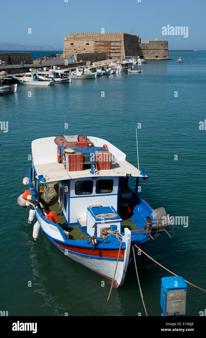 Pescador en barco en el puerto de Heraclion, la fortaleza veneciana de Koules en el fondo, Creta, Grecia Foto de stock