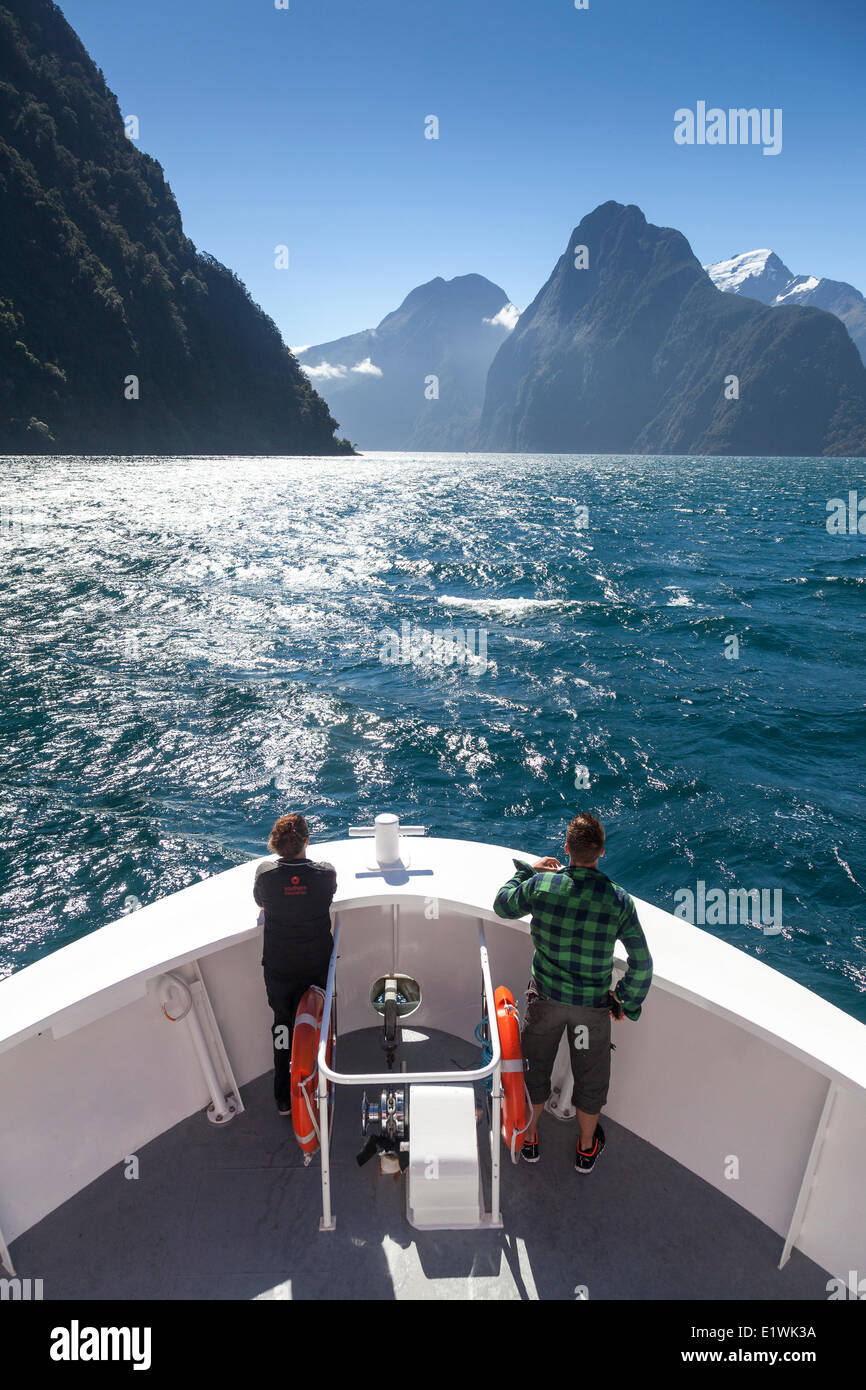 Los turistas en la proa de un barco en Milford Sound en frente del Mitre Peak en el Parque Nacional Fiordland, Nueva Zelanda Foto de stock