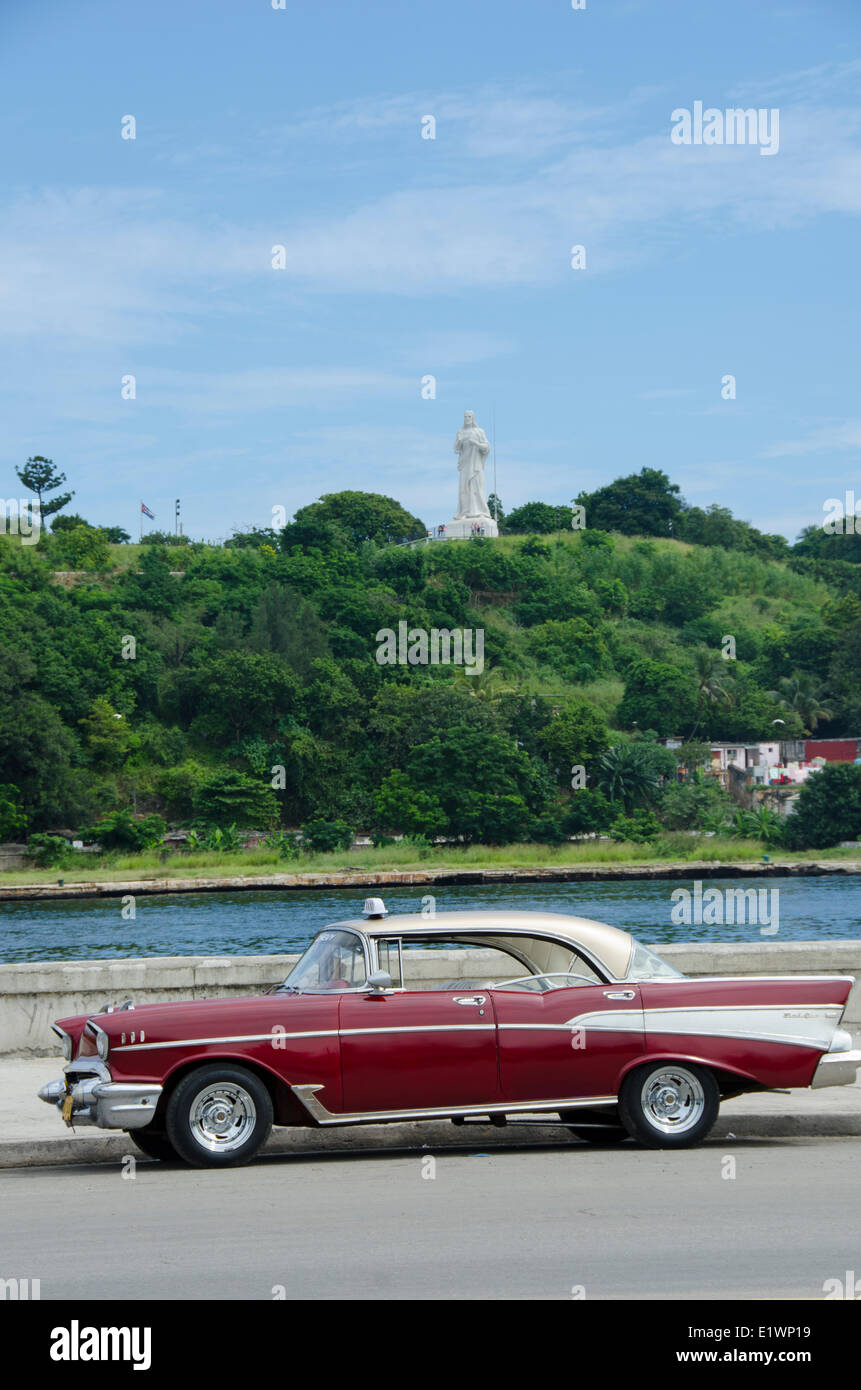 Viejo Chevy Bel Air como taxi con Cristo de La Habana aumentando a través de todo puerto, La Habana, Cuba Foto de stock