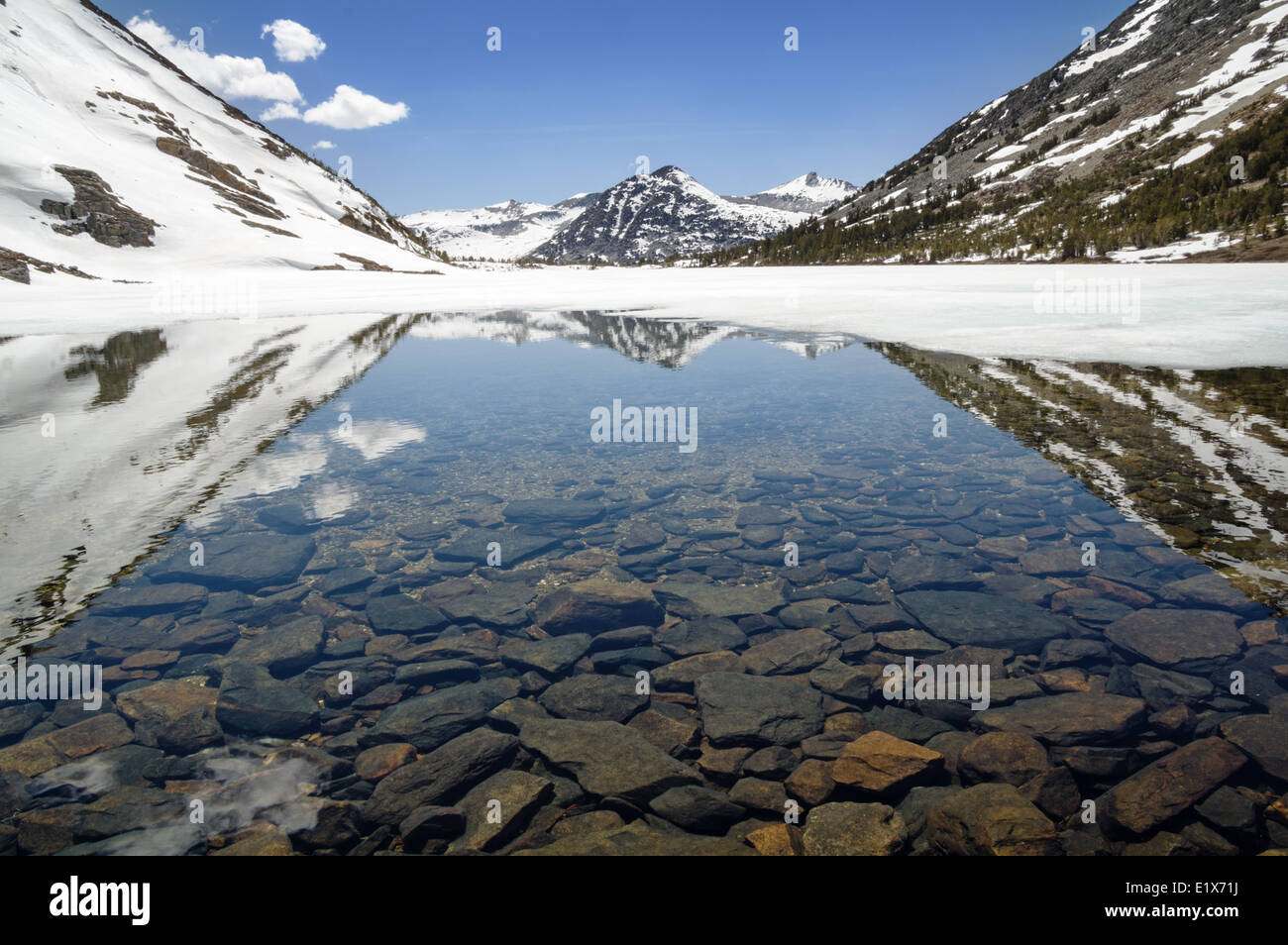 La reflexión de Gris Butte en summit el lago en las montañas de Sierra Nevada como el hielo y la nieve se derrite en la primavera Foto de stock