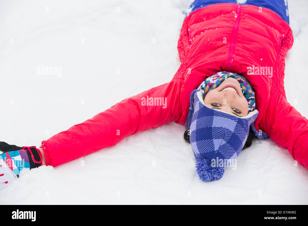 Retrato de mujer sonriente tumbado en la nieve Foto de stock
