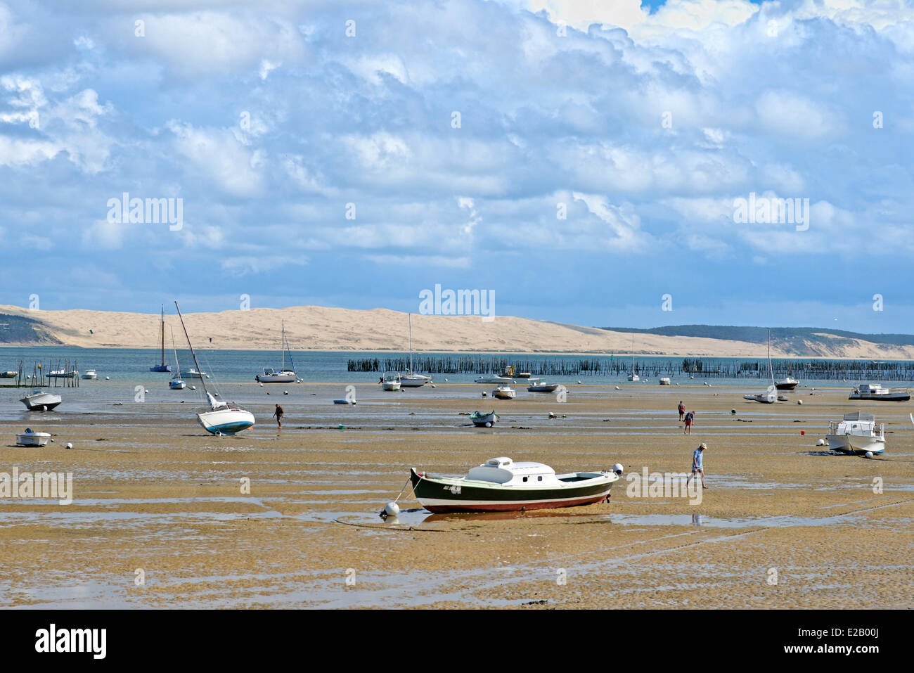 Francia, bahía de Arcachon, Gironde, Cap Ferret, hombres caminando sobre la arena durante la marea baja con barcos en medio de la Dune du Pyla en Foto de stock