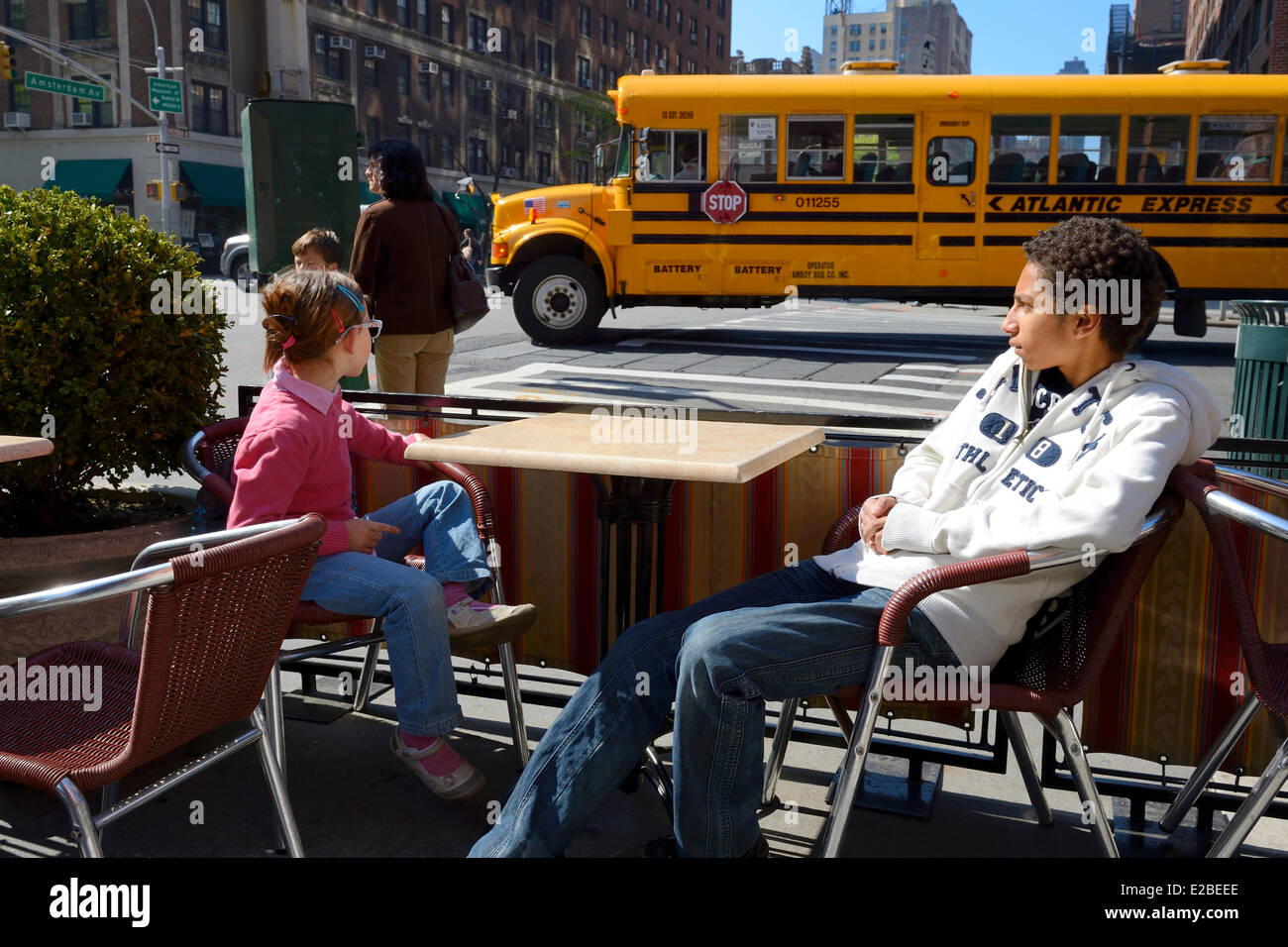 Estados Unidos, la ciudad de Nueva York, Manhattan, Upper West Side, el autobús escolar pasa delante de una terraza de un café en la esquina de 79th Street y la Avenida Amsterdam Foto de stock