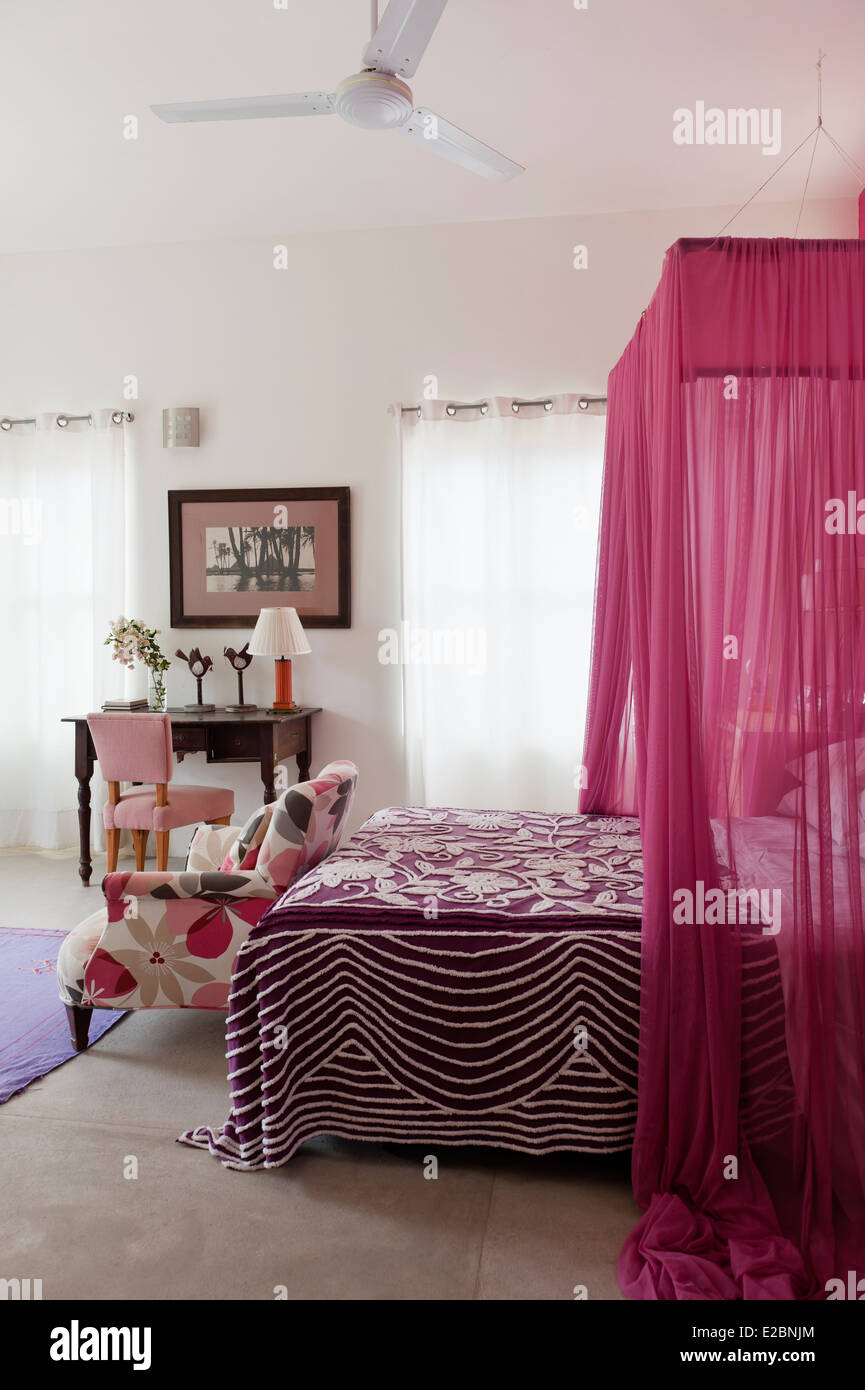 Sillón floral al pie de la cama de color rosa con mosquitero en Baja casa  del diseñador de interiores Jenny Armit inglés Fotografía de stock - Alamy