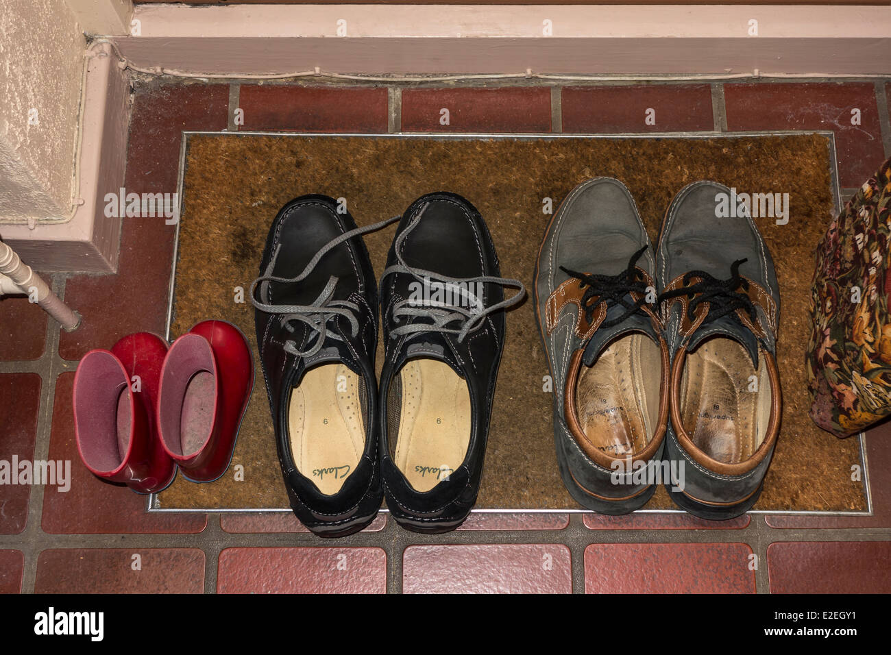 Los zapatos y las pequeñas wellingtons en puerta mat studio Foto de stock
