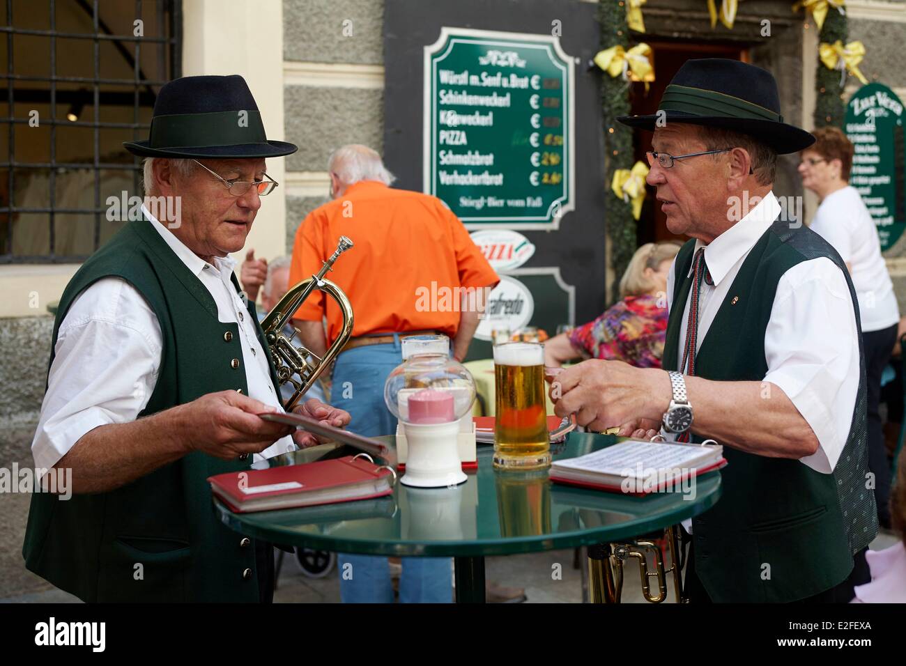 Austria, Salzburgo, trompetistas en traje tradicional bebiendo una cerveza en la terraza del restaurante Foto de stock