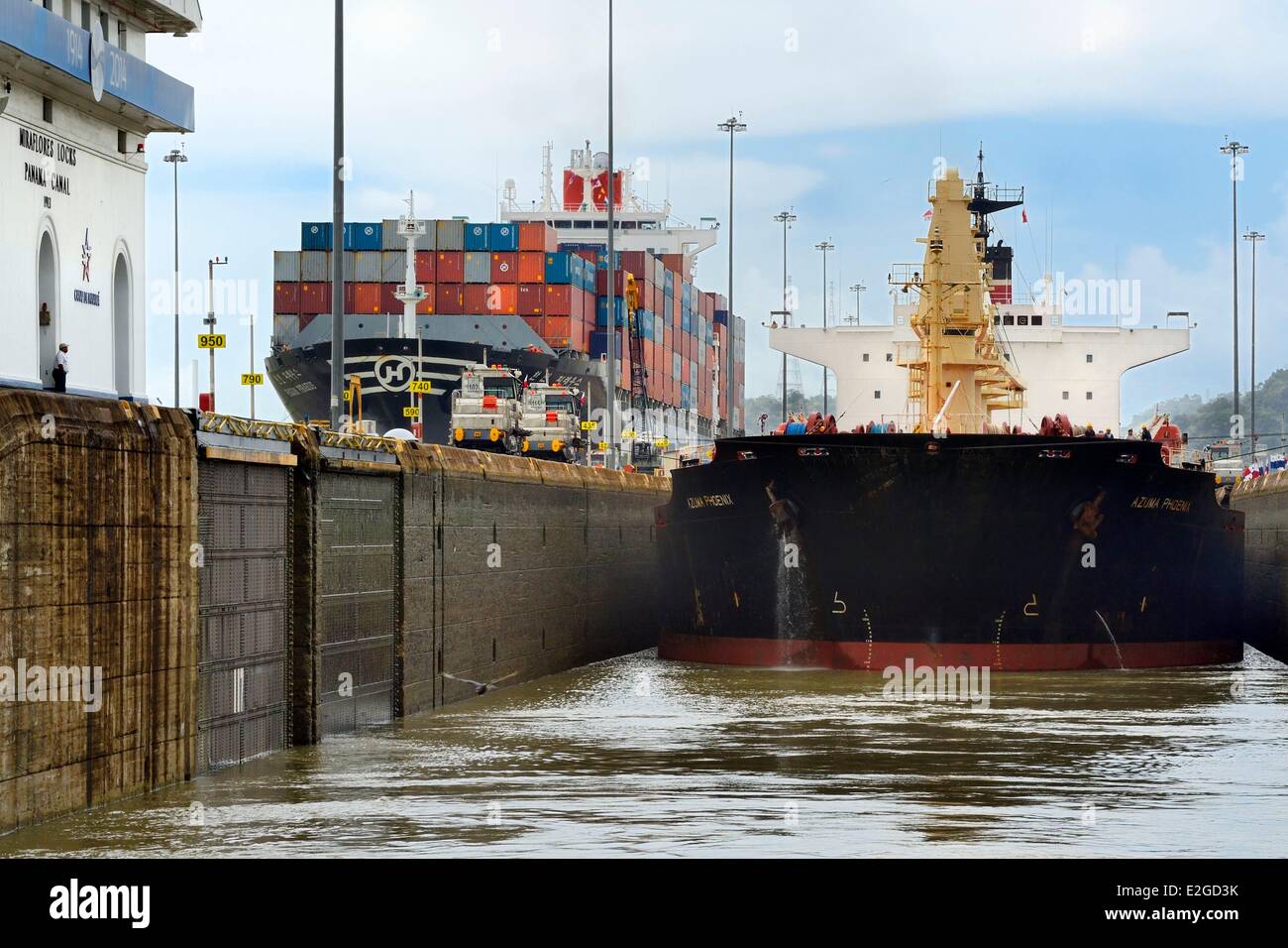 Las esclusas de Miraflores del Canal de Panamá Panamá mecánica mulas o locomotoras eléctricas Panamax guiando un cargamento entre paredes de bloqueo Foto de stock