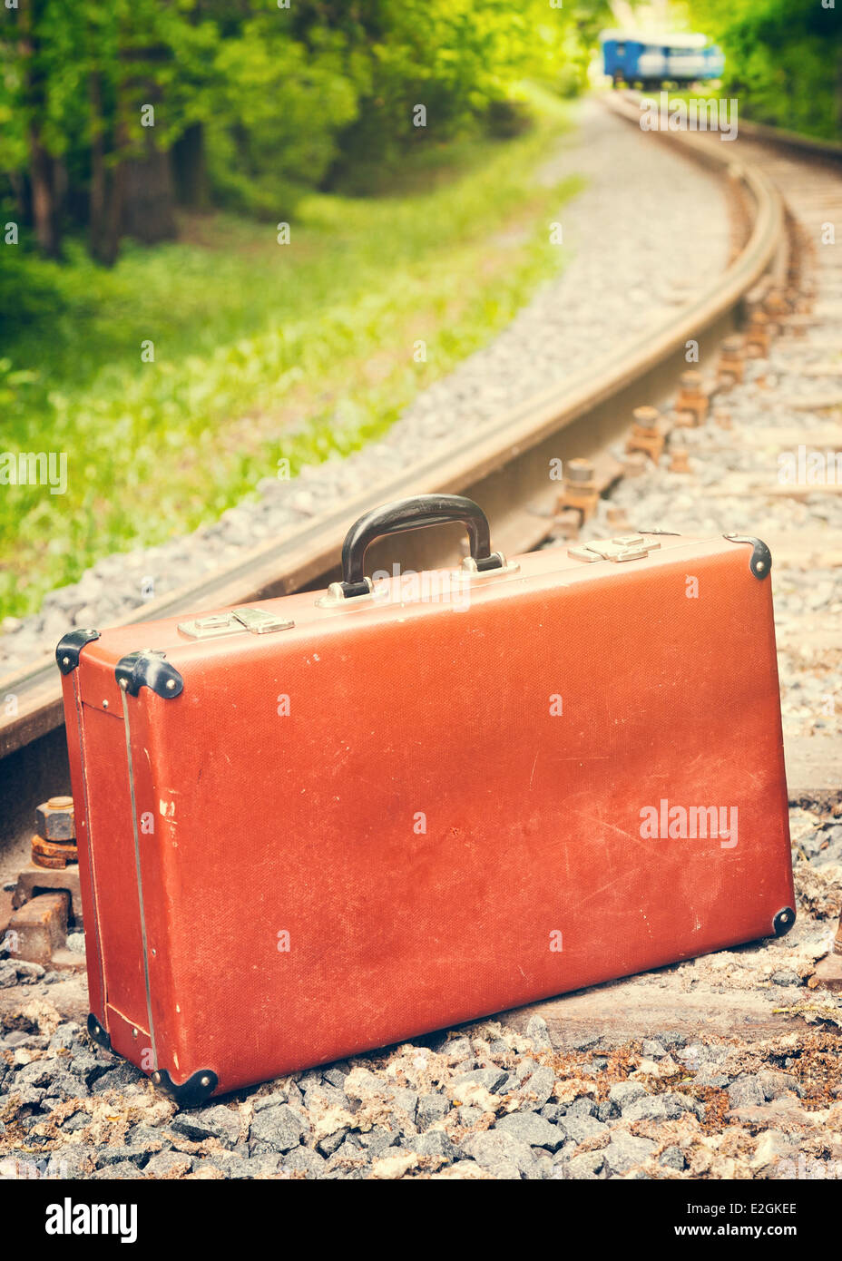 Vintage maletín marrón en el ferrocarril, tren azul está desactivado Foto de stock
