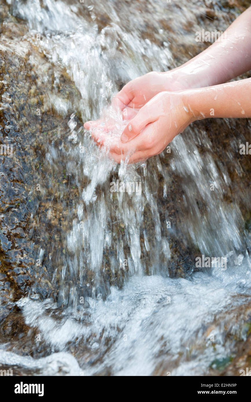 Niño sosteniendo las manos bajo ahuecados, frescas, agua corriente, recortadas Foto de stock