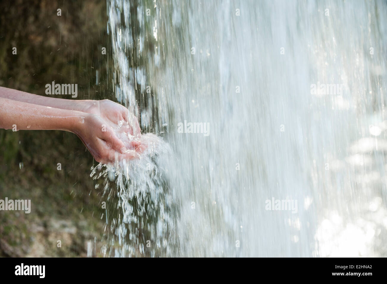 Niño sosteniendo las manos debajo de la cascada, recortadas Foto de stock