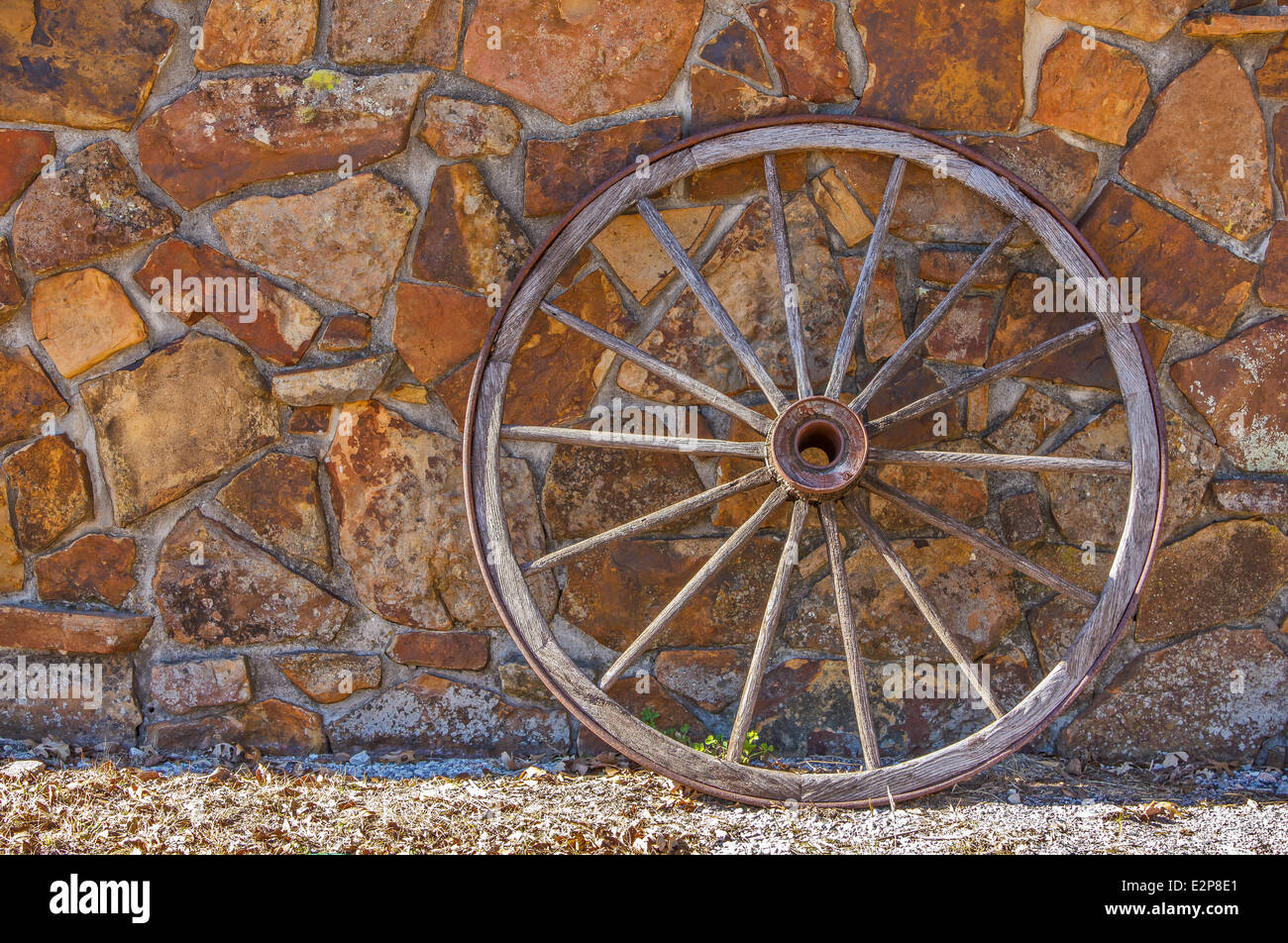 Un viejo Wagon Wheel contra una pared de piedra Foto de stock