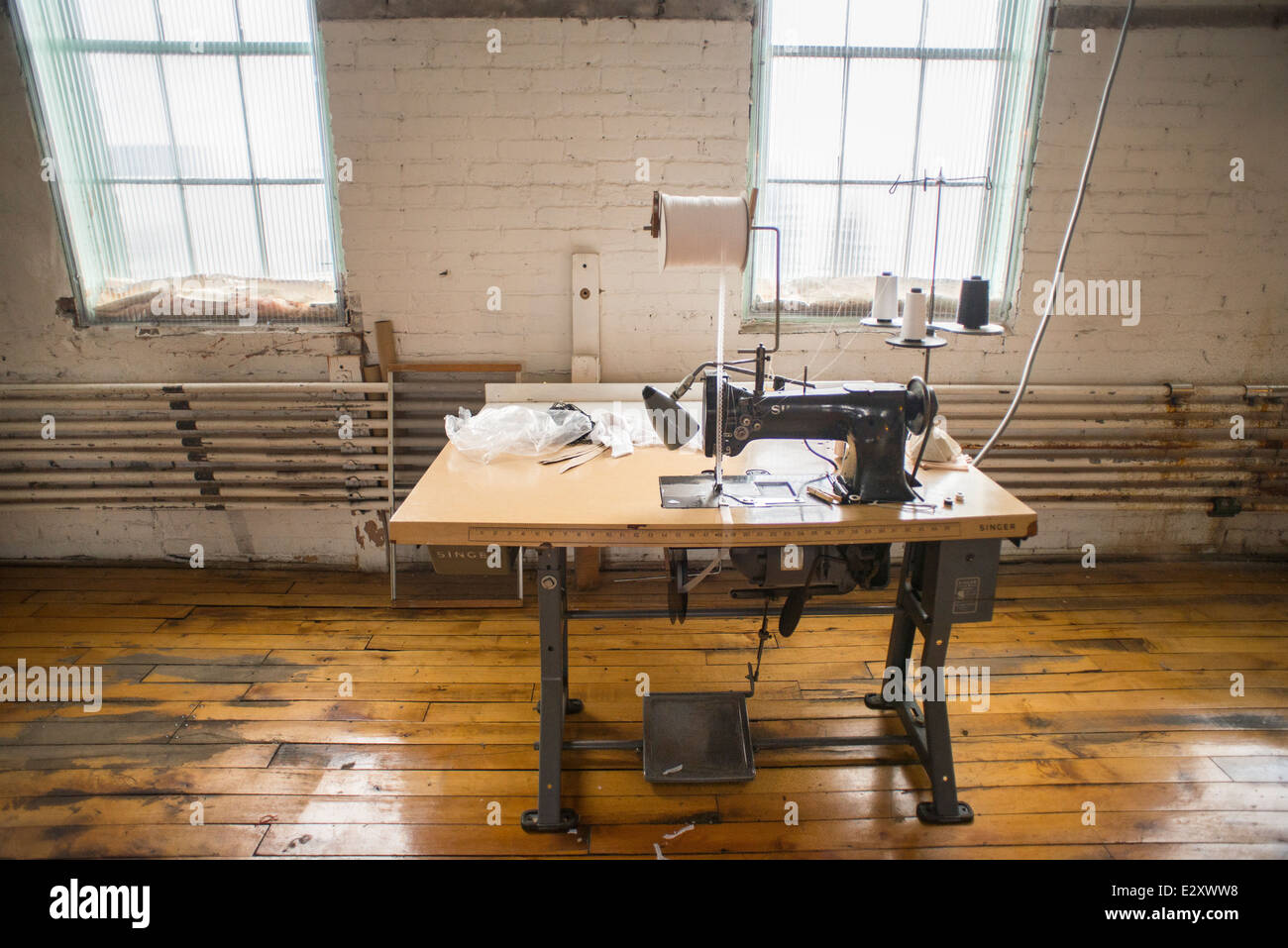 Una antigua máquina de coser Singer negro conectado a una mesa antigua con  un pedal de pie se sienta en un corsé de fábrica en Cortland, NY Fotografía  de stock - Alamy