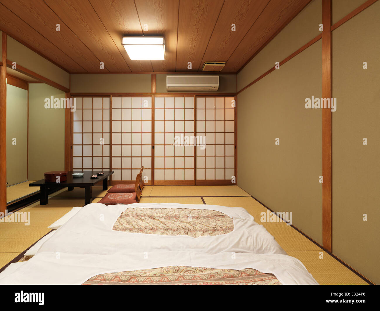 Futón japonés en salón japonés con mesa baja y jarrones en el suelo