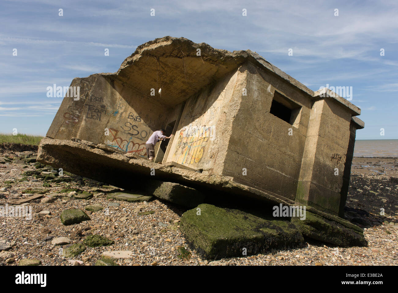 WW2-era pastillero defensa concreta estructura yace en la playa después de la erosión costera en Warden Point, en la isla de Sheppey, Kent. Foto de stock