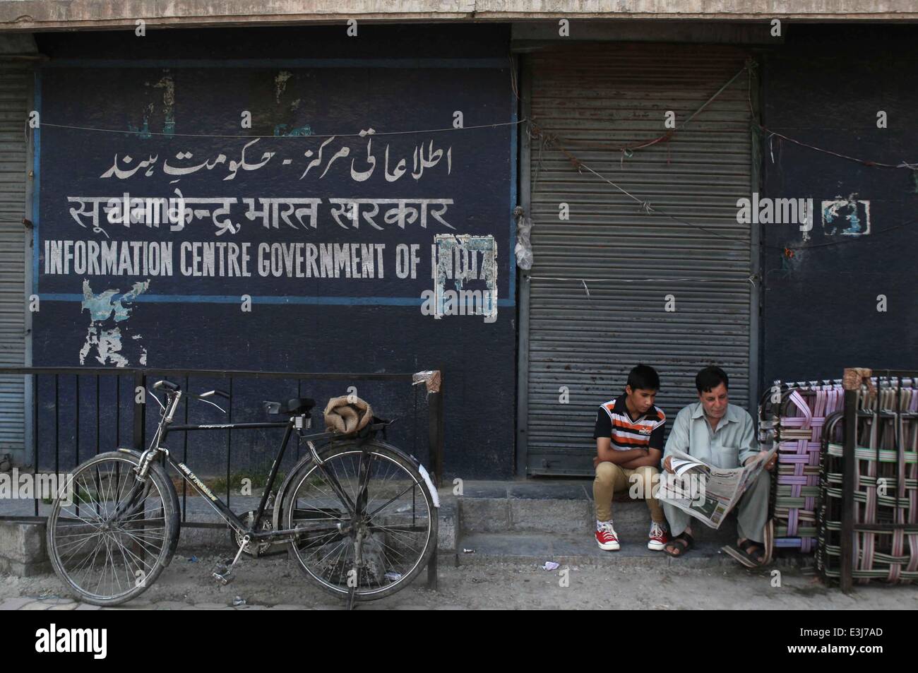 (140624) - Srinagar, 24 de junio de 2014 (Xinhua) -- un hombre y su hijo de Cachemira leer un periódico fuera de una tienda cerrada durante una huelga en Srinagar, la capital de verano de la Cachemira india, 24 de junio de 2104. La vida normal en zonas de mayoría musulmana de la Cachemira india incluyendo la ciudad de Srinagar fue afectada el martes debido a un cierre separatista. La parada llamada fue dada por el grupo separatista de la región para protestar por el asesinato de un joven cuando las tropas indias dispararon contra manifestantes el lunes. Las protestas estallaron en Krank Shivan en Sopore ciudad, a unos 54 km al noroeste de la ciudad de Srinagar siguiendo los kil Foto de stock
