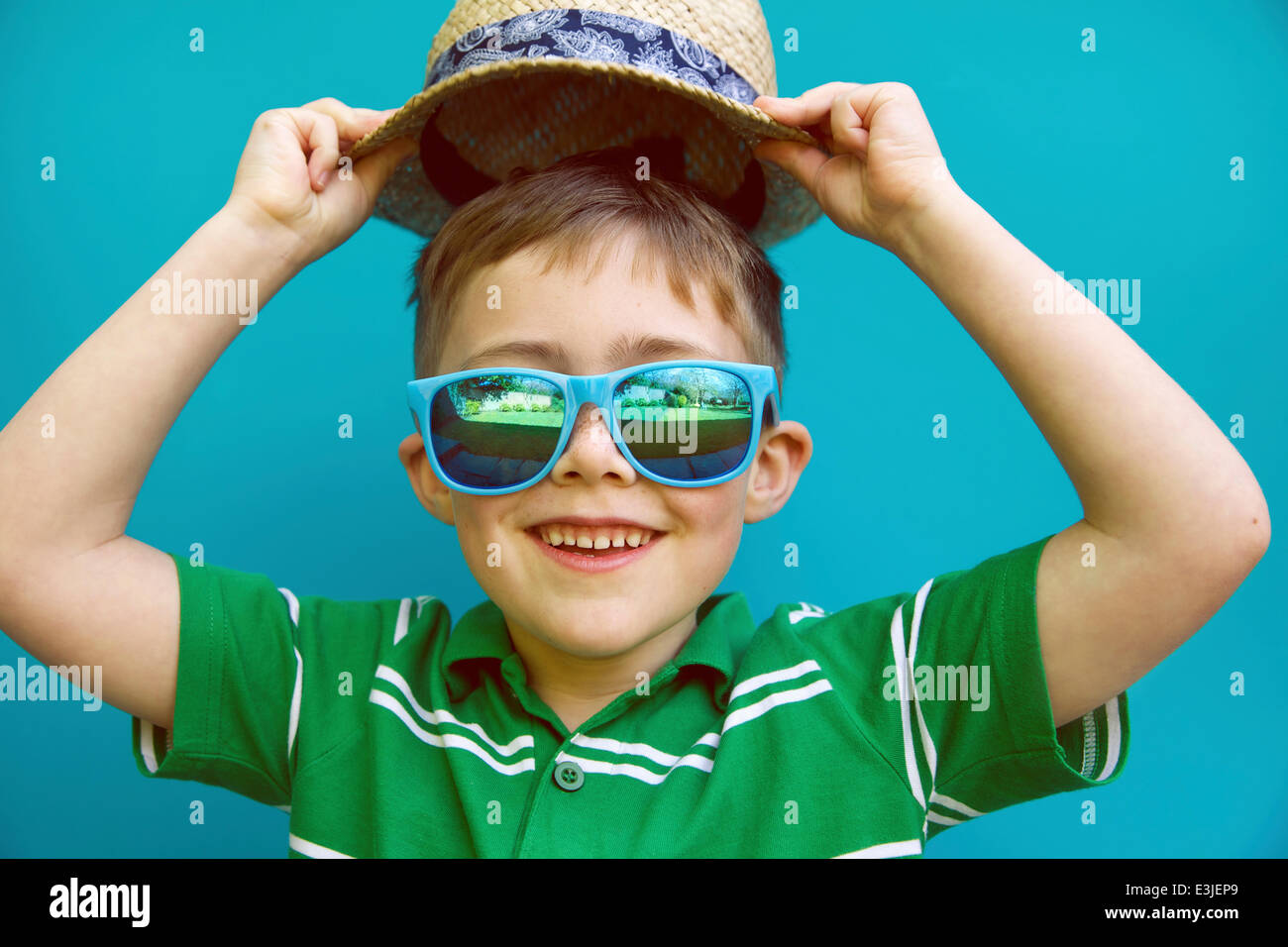 Sonriente niño usando sombrero de paja y gafas de sol Foto de stock