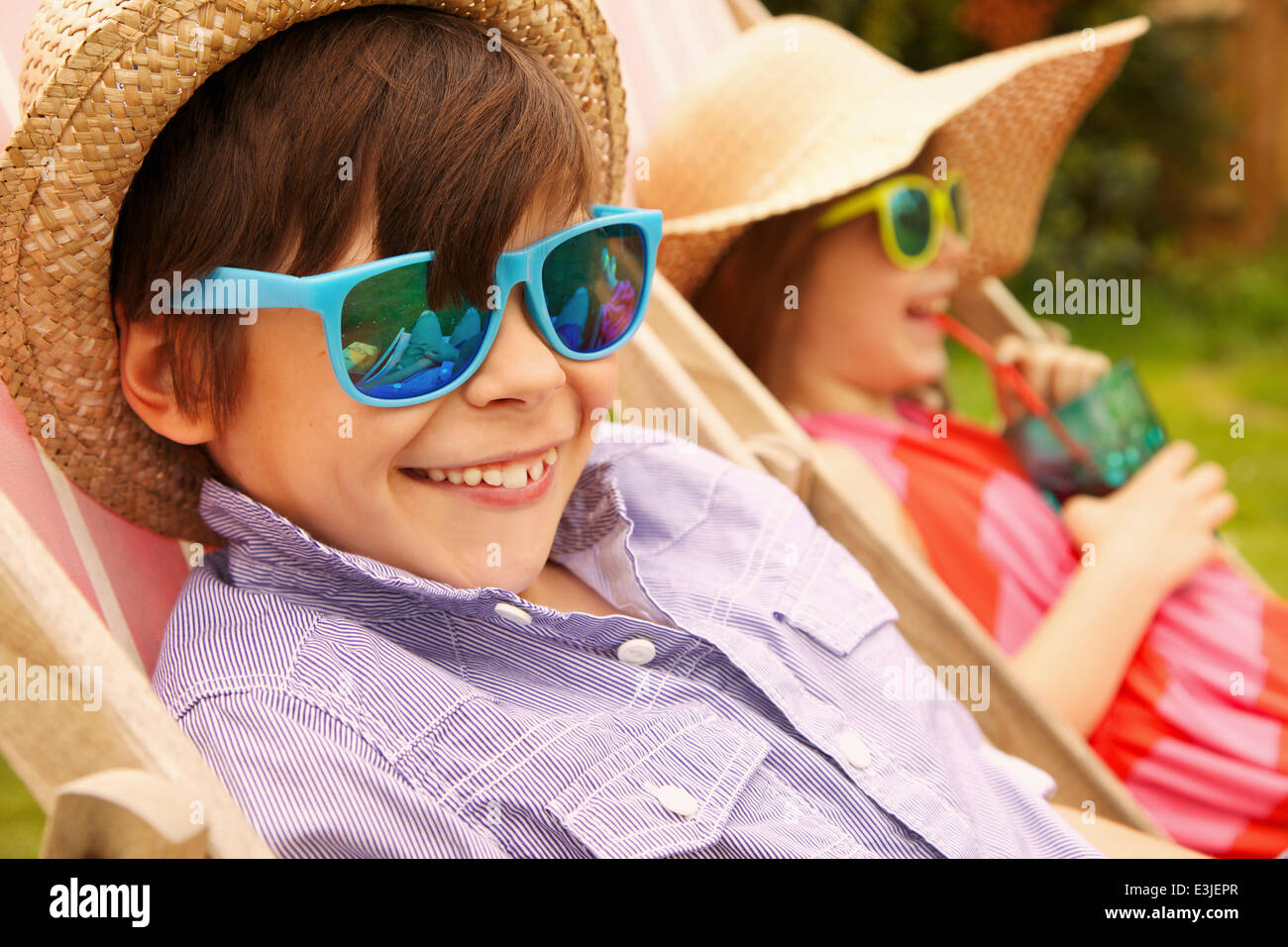 Chico y chica luciendo sombrero de paja y gafas de sol sonriente Foto de stock