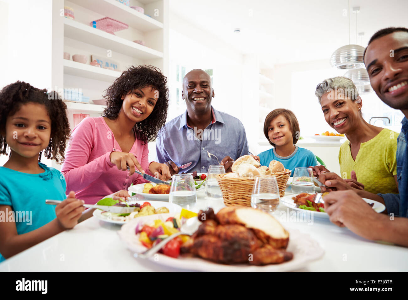 Varias generaciones de la familia afroamericana comiendo comida en casa Foto de stock