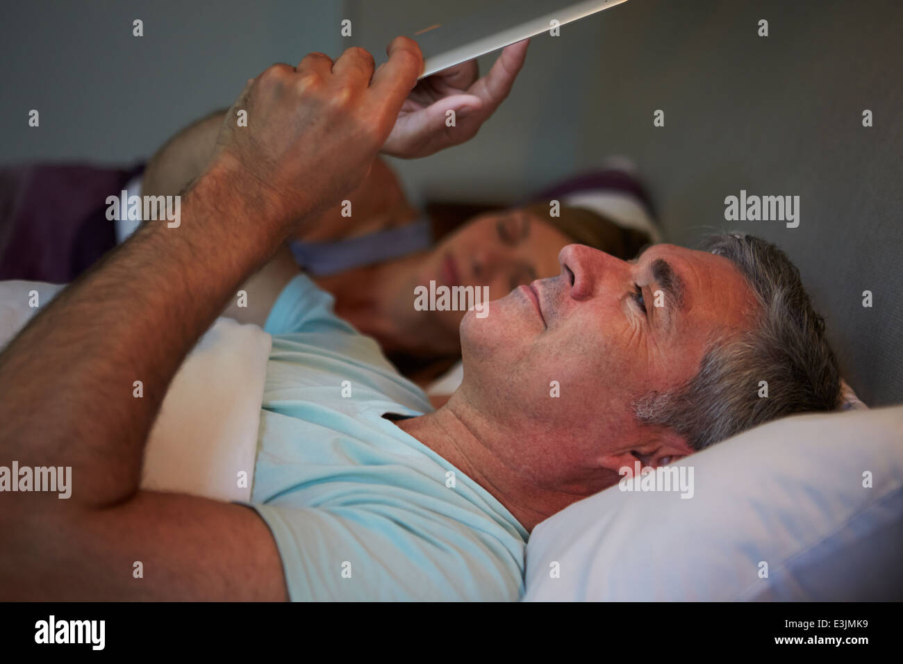 Pareja de mediana edad en la cama con el hombre con Tablet PC Foto de stock
