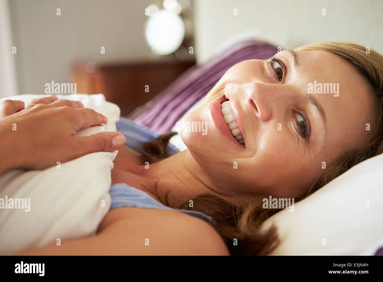 Atractiva mujer de mediana edad de despertarse en la cama Foto de stock