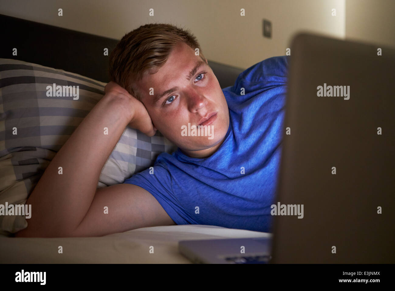 Adolescente con laptop en la cama por la noche Foto de stock