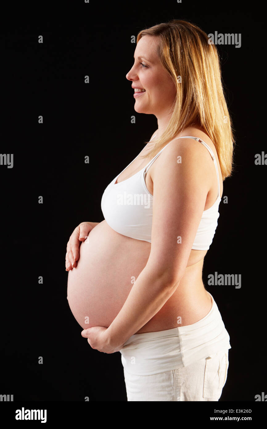 Retrato de mujer embarazada vestidos de blanco sobre fondo negro Foto de stock