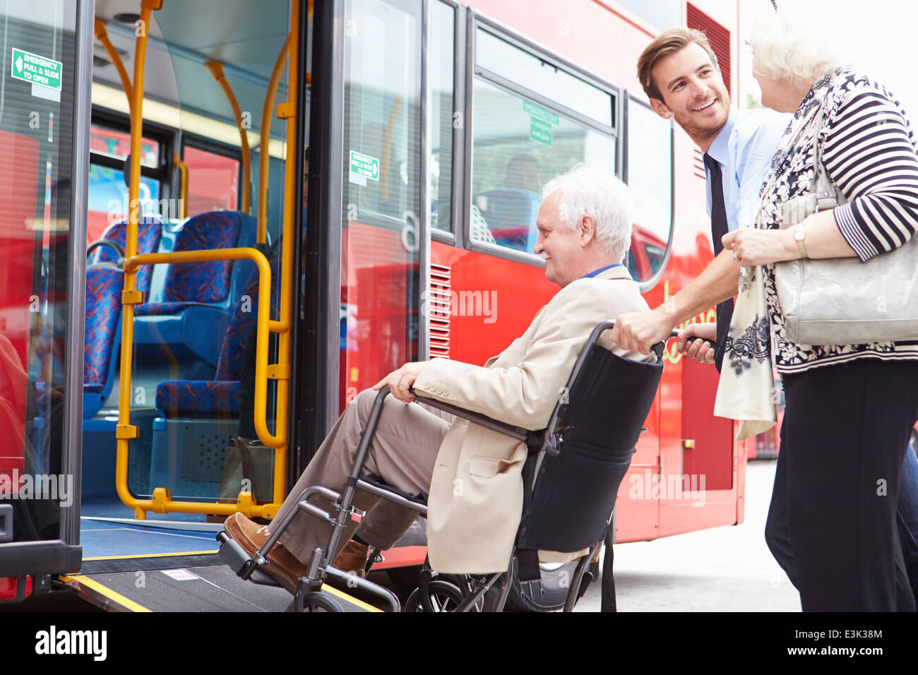 Ayudar a las parejas ancianas junta controlador Bus a través de rampa para sillas de ruedas Foto de stock