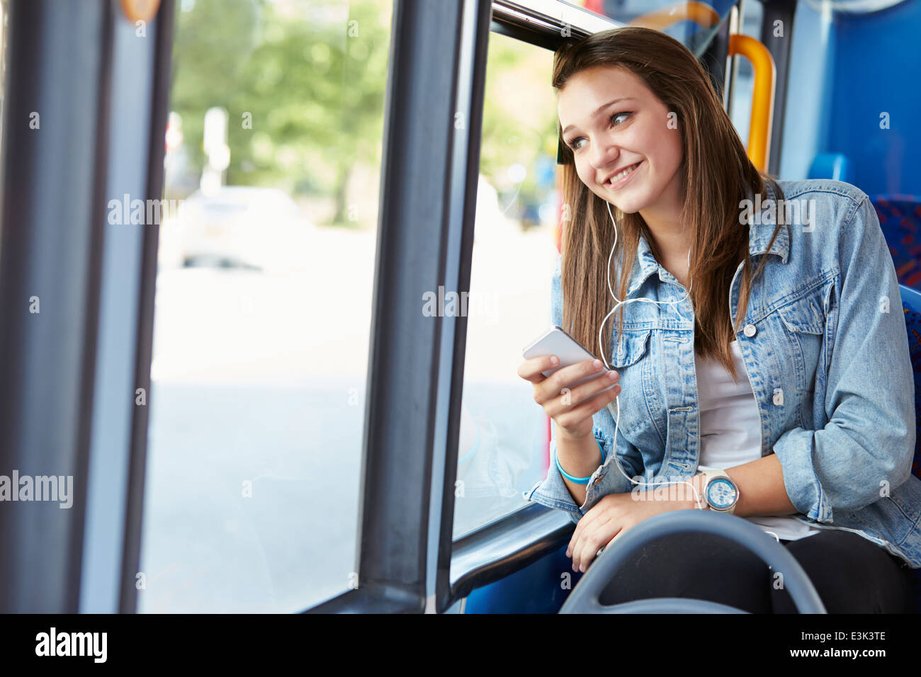 Adolescente portando auriculares para escuchar música en el bus Foto de stock