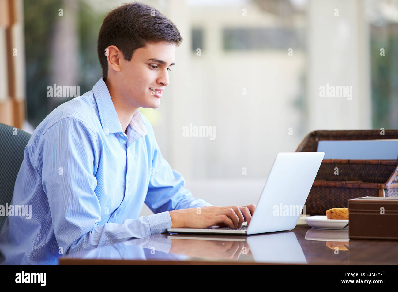 Adolescente utilizando el portátil en el escritorio en el hogar Foto de stock