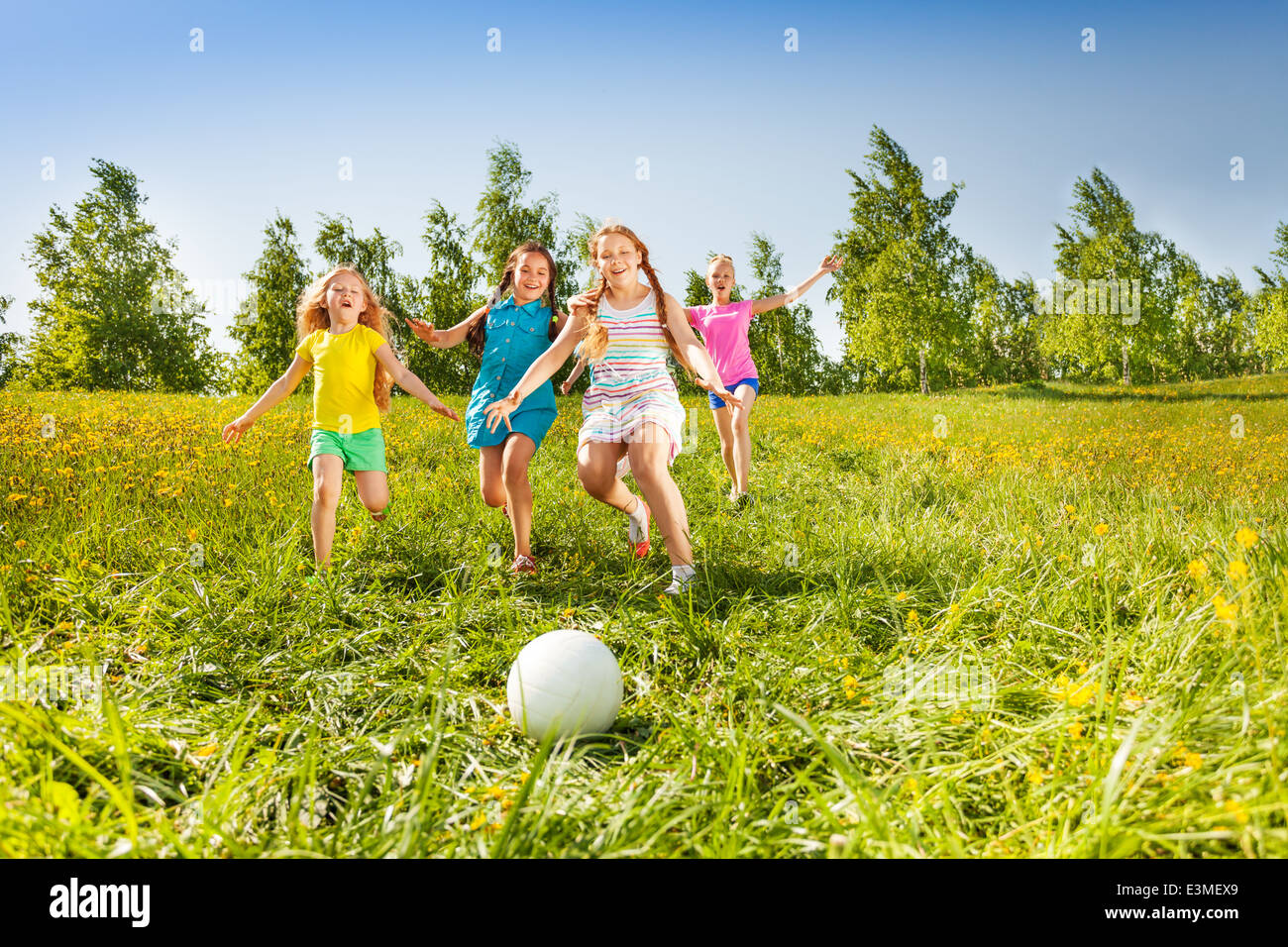 Un grupo de niños corriendo a la bola en la pradera Foto de stock