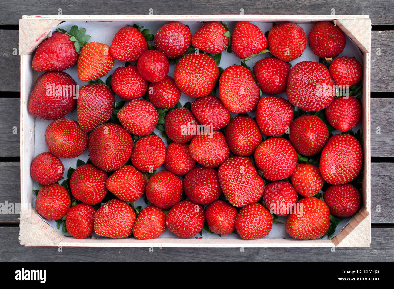 Caja de madera de pequeñas fresas rojas Foto de stock