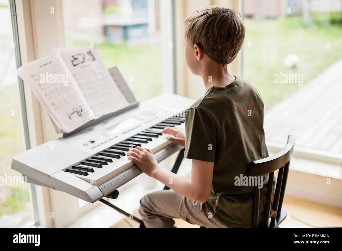 Vista trasera de chico tocando el piano en casa Fotografía de stock - Alamy